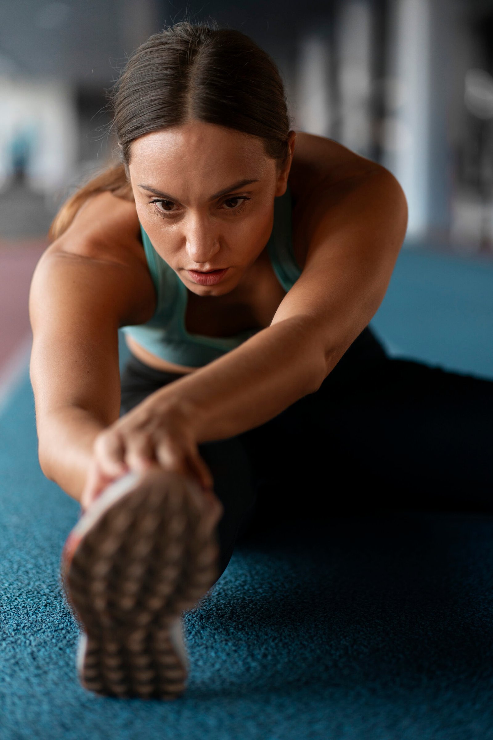 Persona realizando un estiramiento en colchoneta azul, vestida con ropa deportiva, mostrando enfoque y bienestar físico